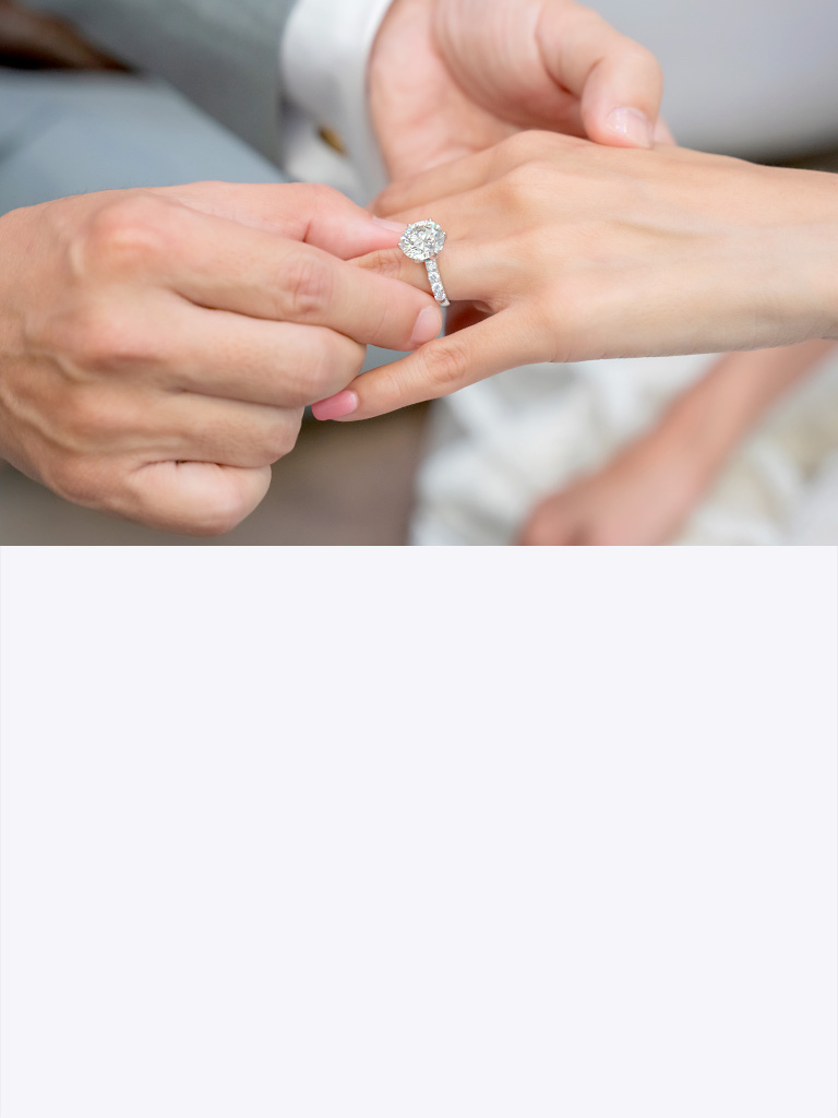 Man placing an engagement ring onto a woman's finger