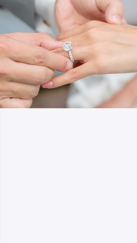 Man placing an engagement ring onto a woman's finger