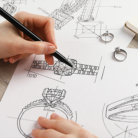 Person sketching a ring design on a piece of paper